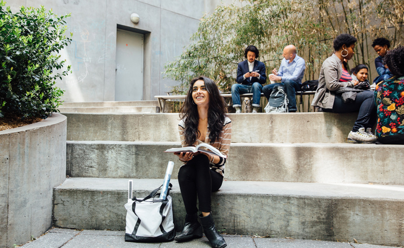 A student taking continuing education classes lounges on the steps of the Vera List Courtyard at 66 West 12th Street.