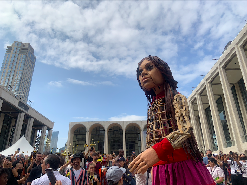 The giant puppet, who is a Syrian refugee child, danced alongside a brass band in the world famous Plaza, while onlookers of all ages and backgrounds looked on